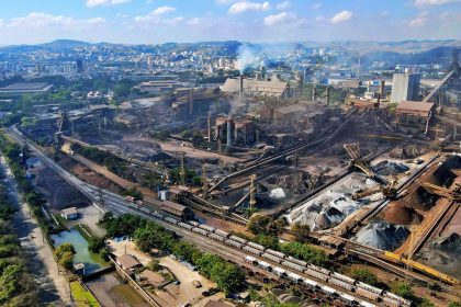 Vista aérea de uma área industrial no Rio de Janeiro, com fábricas e edifícios urbanos ao redor.